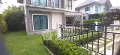 Modern two-story house with lush garden and sleek fence in suburban neighborhood.