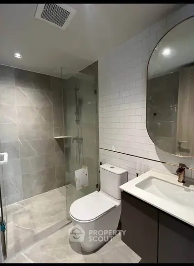 Modern bathroom with glass shower, sleek fixtures, and elegant tile design.
