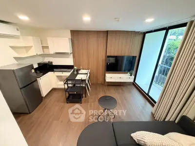 Modern open-layout living room with kitchen, featuring sleek design and large windows for natural light.