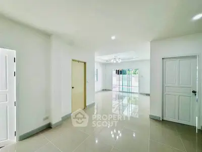 Spacious and bright living area with glossy tiled floors and modern lighting, perfect for family gatherings.