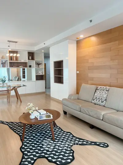 Modern living room with stylish decor and open dining area, featuring wooden accents and cozy seating.