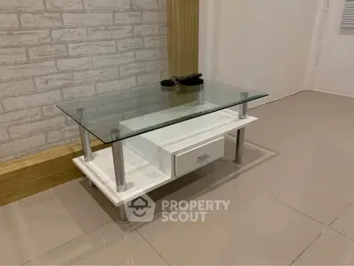 Modern living room with stylish glass coffee table and sleek tile flooring.