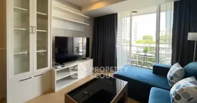 Modern living room with large TV, stylish furniture, and balcony view in urban apartment.