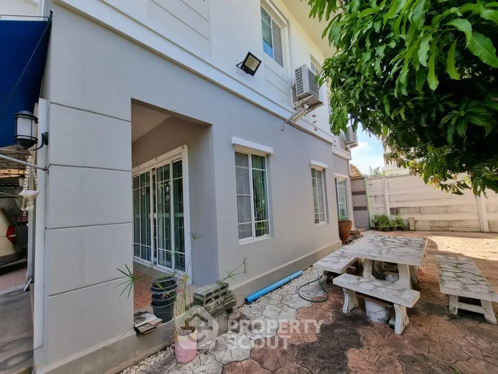 Charming exterior view of a modern home with a cozy outdoor seating area and lush greenery.