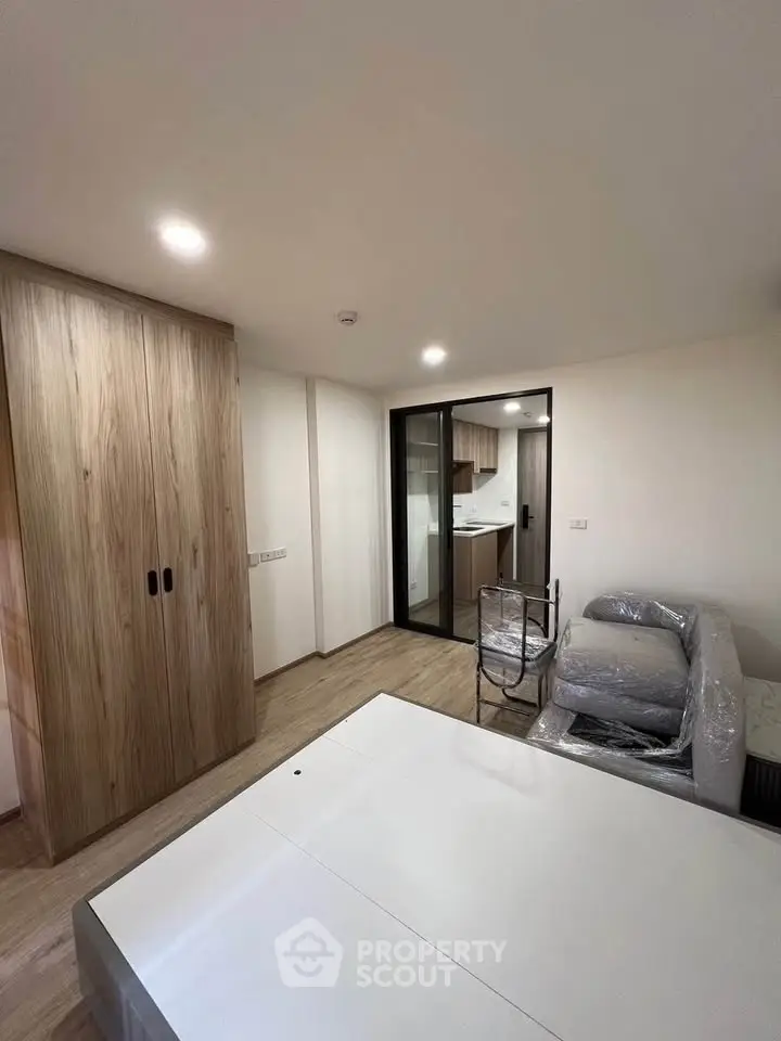 Modern living room with wooden flooring and open kitchen layout in a stylish apartment.