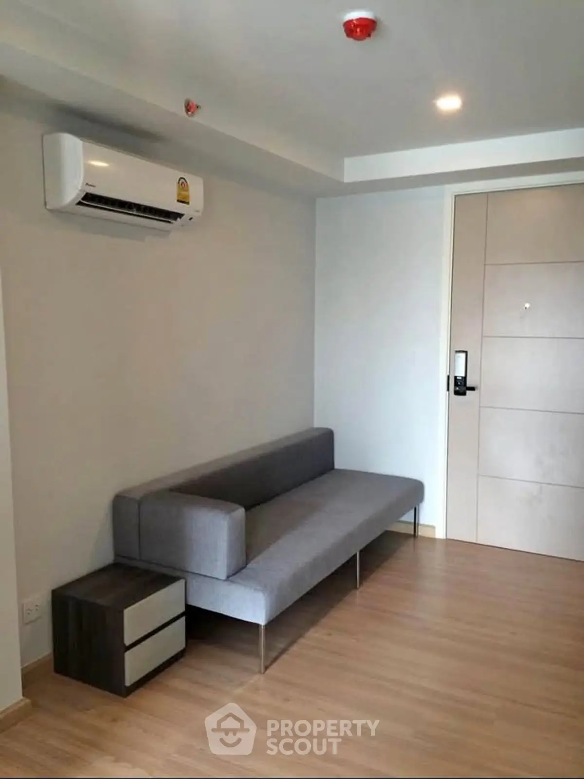 Modern living room with sleek gray sofa and air conditioning in a minimalist apartment.