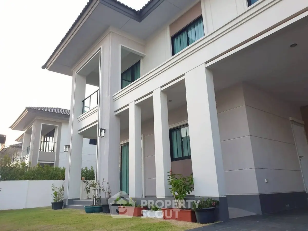 Modern two-story house with elegant facade and lush garden in a serene neighborhood.