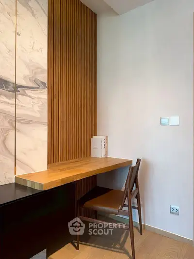 Modern study nook with wooden desk and chair, featuring elegant wall paneling.