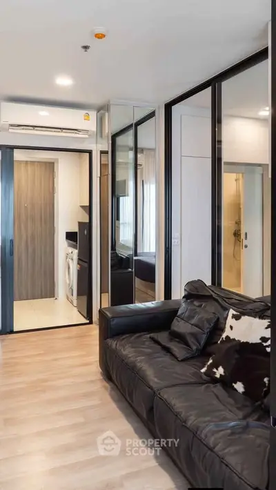 Modern living room with leather sofa and mirrored walls in a stylish apartment.