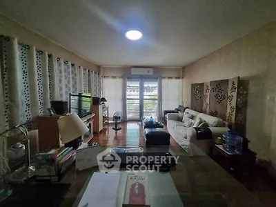 Spacious living room with modern decor and large windows offering natural light and garden view.