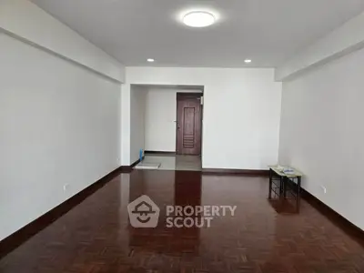 Spacious empty living room with wooden flooring and bright lighting