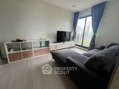 Modern living room with large window and city view, featuring a sleek sofa and entertainment unit.