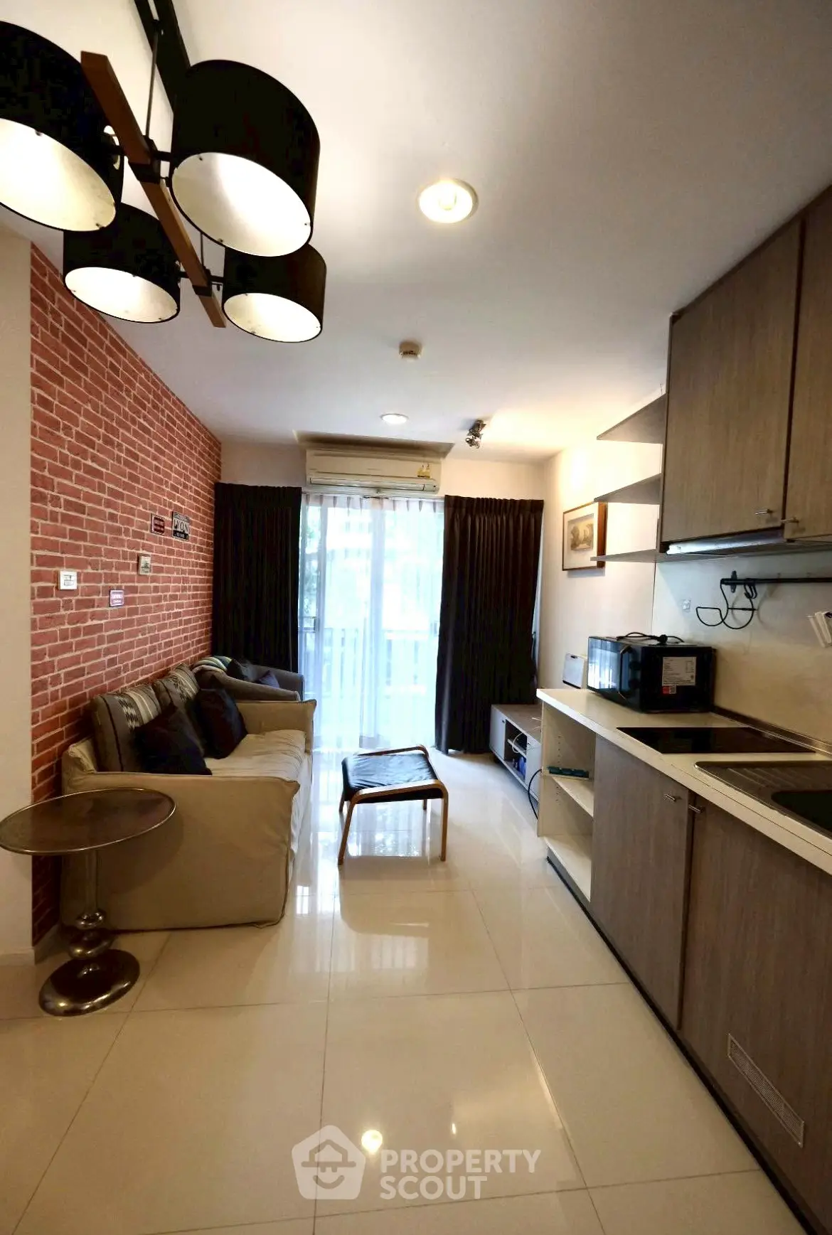 Chic modern living room with brick accent wall and open kitchen layout in cozy apartment.