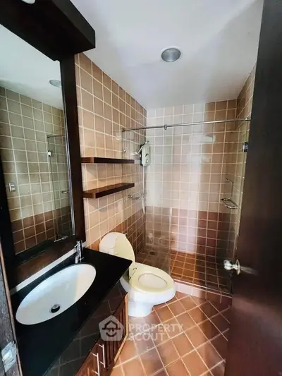 Modern bathroom with tiled walls, sleek sink, and spacious shower area.