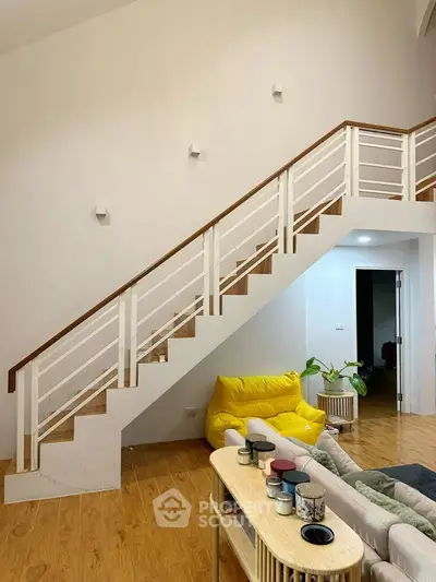 Stylish modern living room with wooden staircase and cozy seating area.