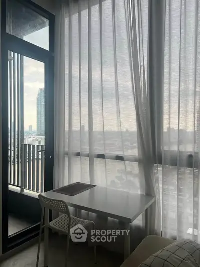 Modern apartment with floor-to-ceiling windows and city view, featuring a cozy workspace.