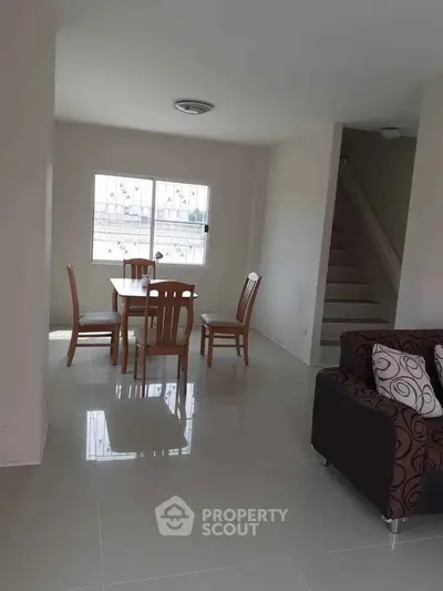 Spacious living area with dining set and modern staircase in a bright home interior.