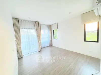 Bright and spacious empty room with large windows and wooden flooring, perfect for customization.