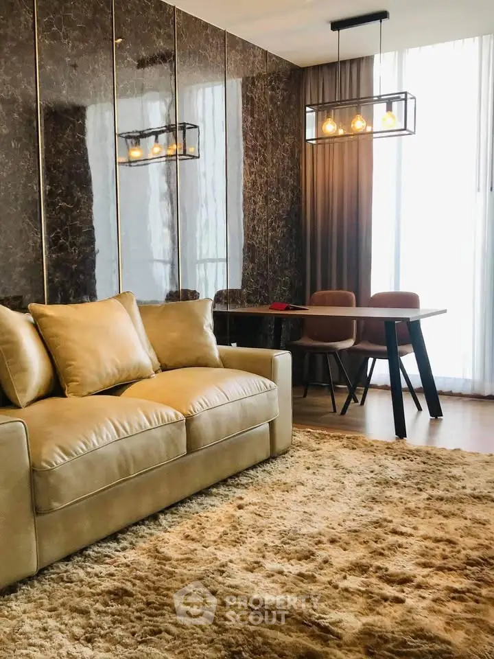Luxurious living room with plush sofa and elegant dining area, featuring modern lighting and floor-to-ceiling windows.