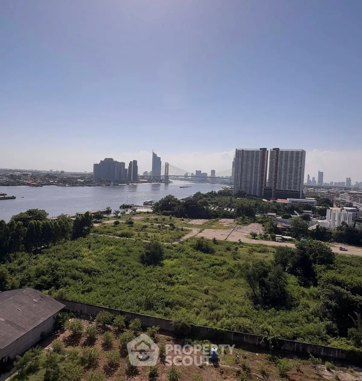 Stunning riverfront view with lush greenery and modern high-rise buildings.