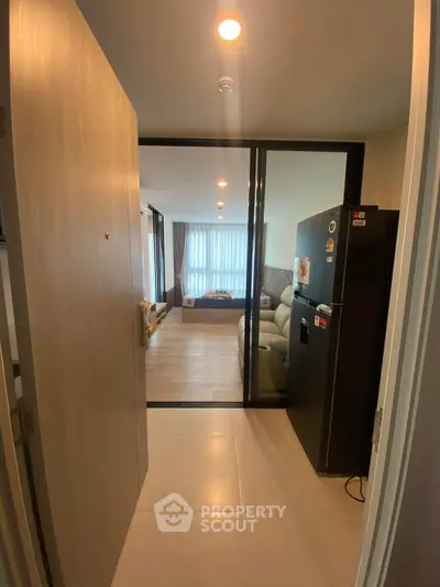 Modern apartment entrance with view into spacious living room and sleek kitchen area.
