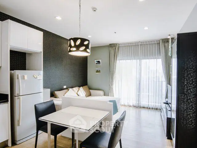 Modern living room with open kitchen, stylish decor, and natural light from large windows.
