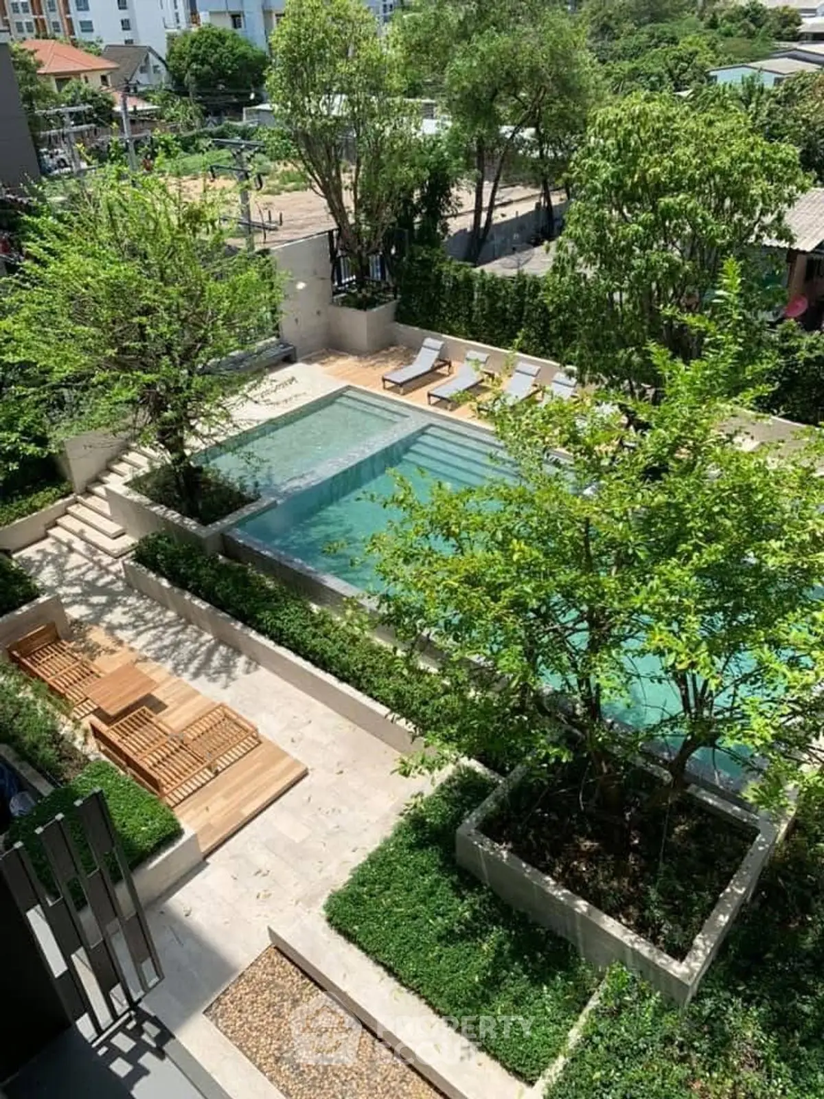 Luxurious outdoor pool area with lush greenery and sun loungers in a serene setting.
