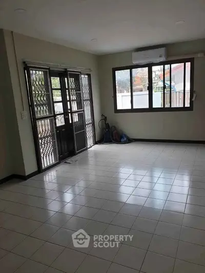 Spacious living room with tiled floor and large windows in a modern home.