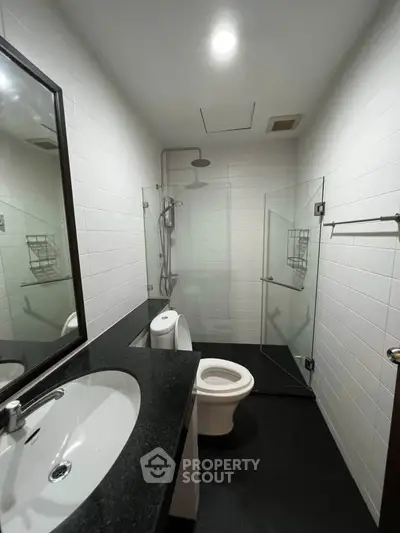 Modern bathroom with sleek black countertop and glass shower enclosure