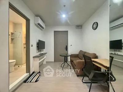 Modern living room with cozy sofa, wall-mounted TV, and adjacent bathroom in a stylish apartment.
