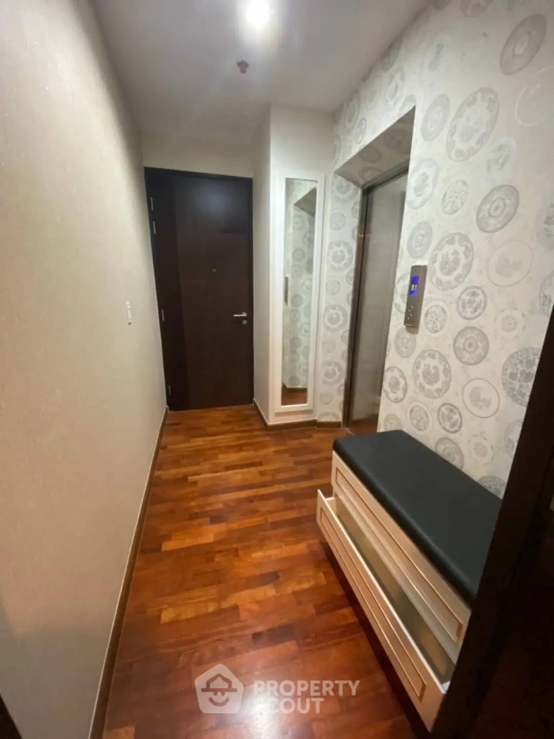 Stylish apartment entrance with wooden flooring and modern elevator access.
