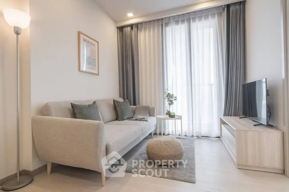 Modern living room with cozy sofa, stylish decor, and natural light from large window.