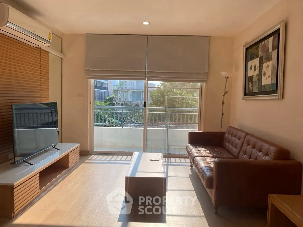 Bright and cozy living room with modern furniture and large window overlooking balcony.