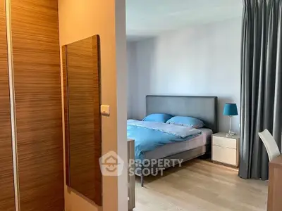 Modern bedroom with stylish decor and wooden flooring, featuring a cozy bed and elegant lighting.