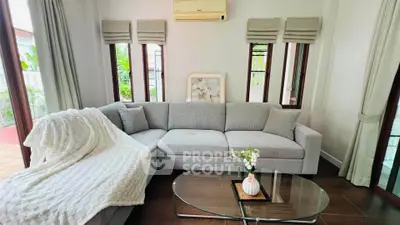 Charming living room with cozy gray sofa, elegant decor, and natural light from large windows.
