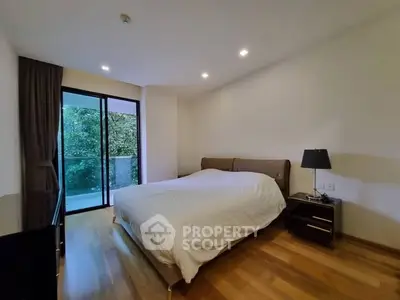 Modern bedroom with balcony view and wooden flooring in a cozy apartment.