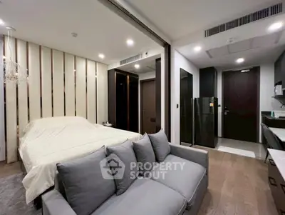 Modern studio apartment with sleek design, featuring a cozy bed, stylish sofa, and compact kitchen area.