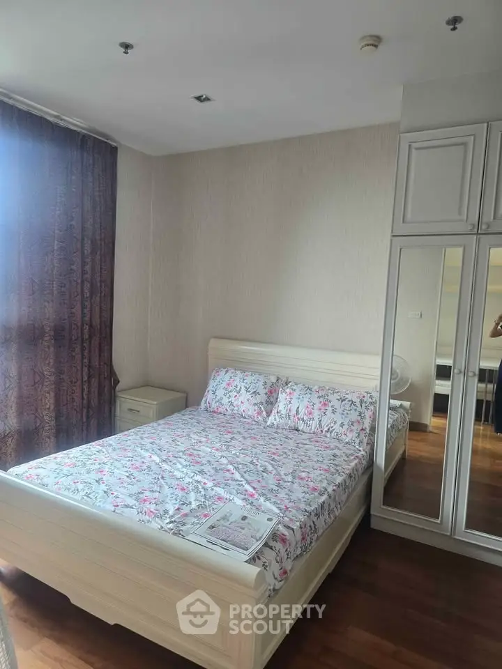 Cozy bedroom with floral bedding and mirrored wardrobe in modern apartment