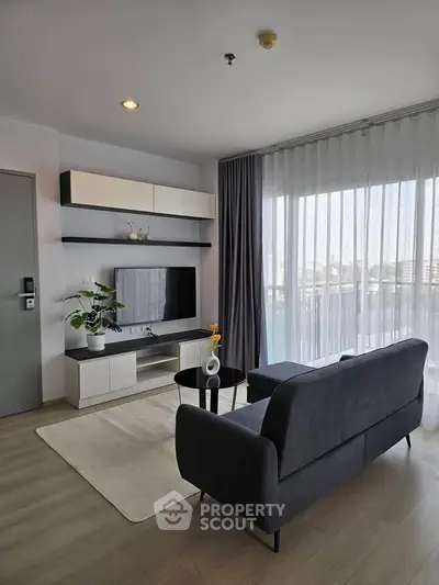 Modern living room with sleek furniture and large window offering natural light