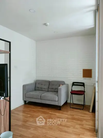 Cozy small living room with modern gray sofa and wooden flooring