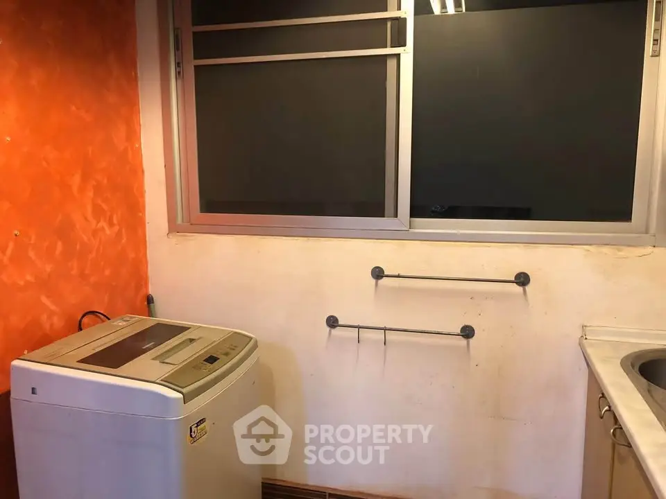 Laundry area with washing machine and orange accent wall