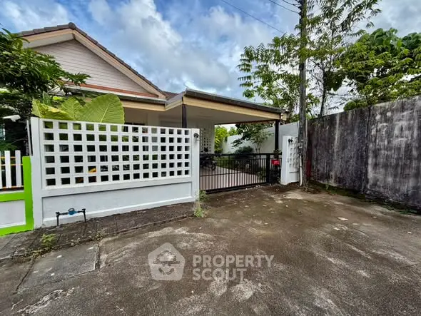 Charming single-story home with gated driveway and lush greenery, perfect for serene living.