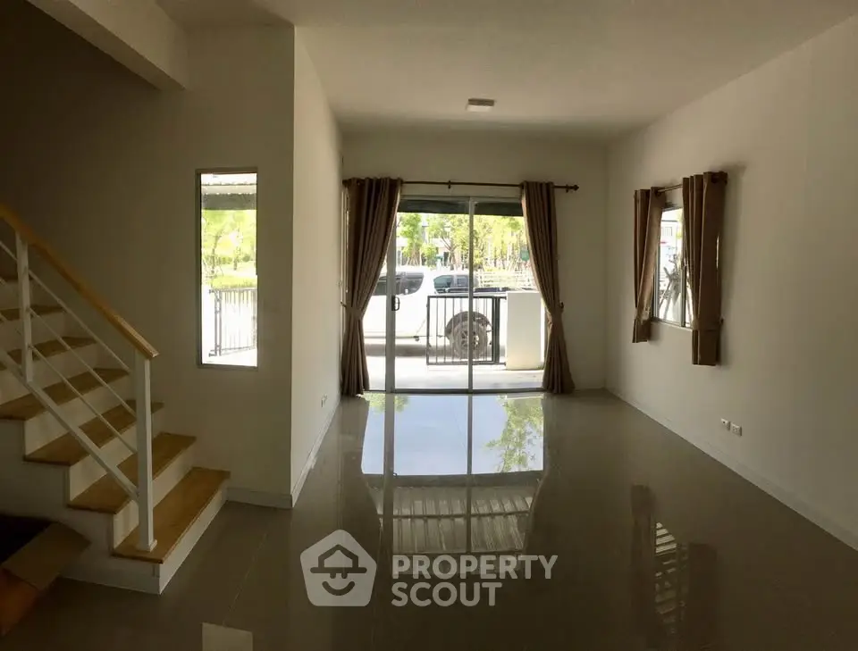 Spacious living room with large windows and modern staircase