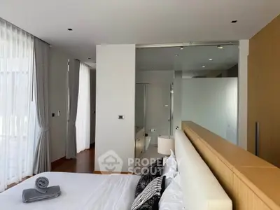 Luxurious bedroom with modern design and glass-enclosed bathroom, featuring elegant decor and natural light.