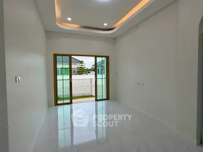 Spacious modern living room with elegant ceiling design and large sliding glass doors opening to a balcony.