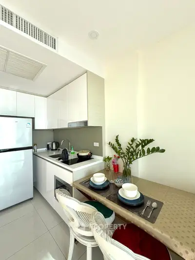 Modern kitchen with dining area, featuring sleek appliances and elegant decor.