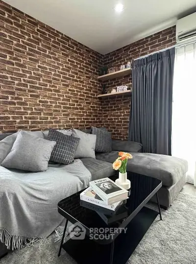 Stylish living room with exposed brick wall and modern gray sofa