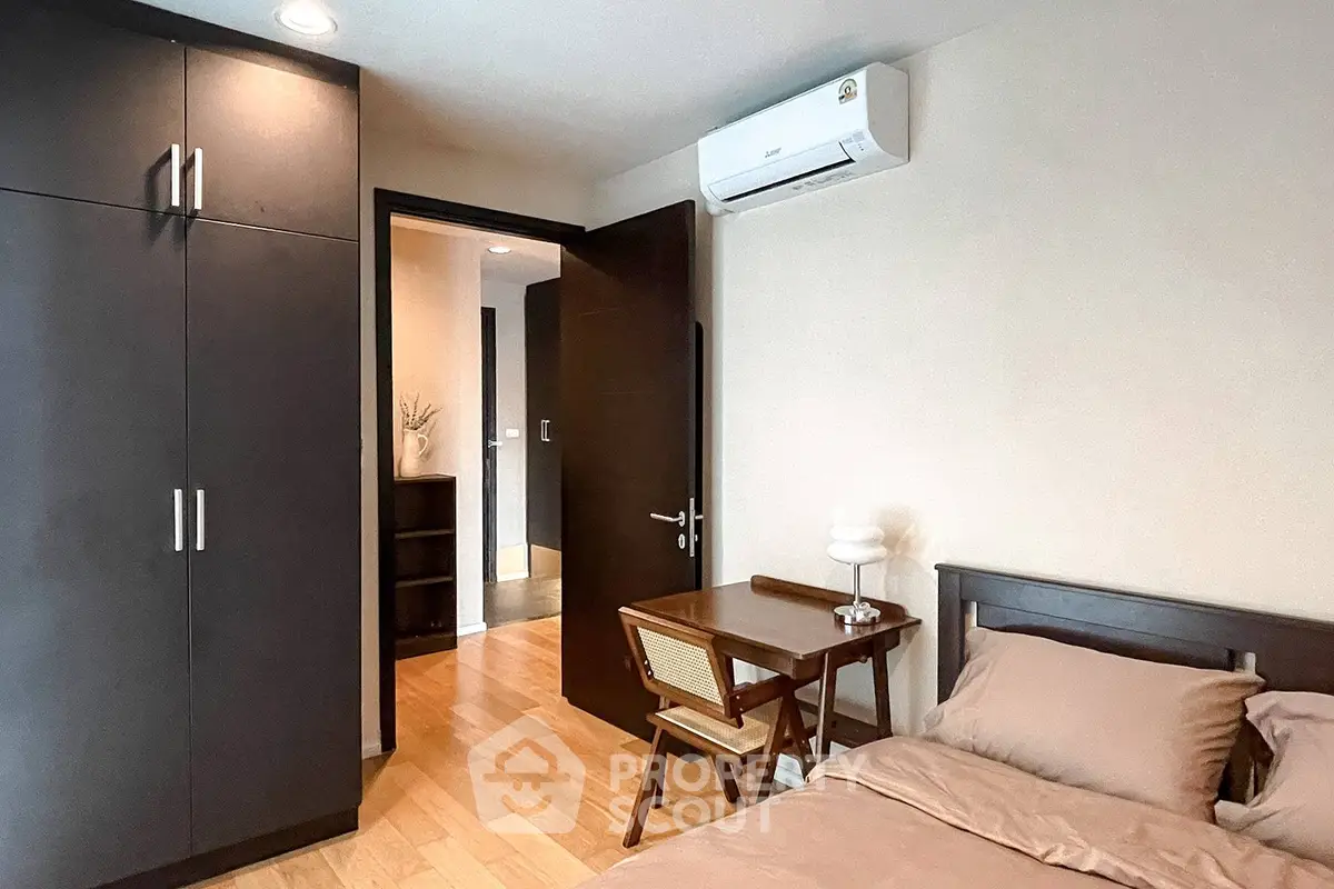 Cozy bedroom with wooden furniture and air conditioning, perfect for relaxation.