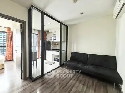 Modern apartment with sleek kitchen and cozy living area, featuring stylish flooring and glass partition.
