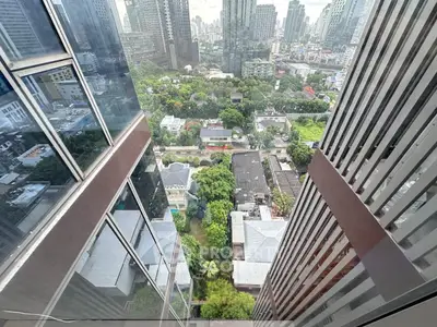 Stunning high-rise city view from a modern skyscraper, showcasing urban landscape and lush greenery below.
